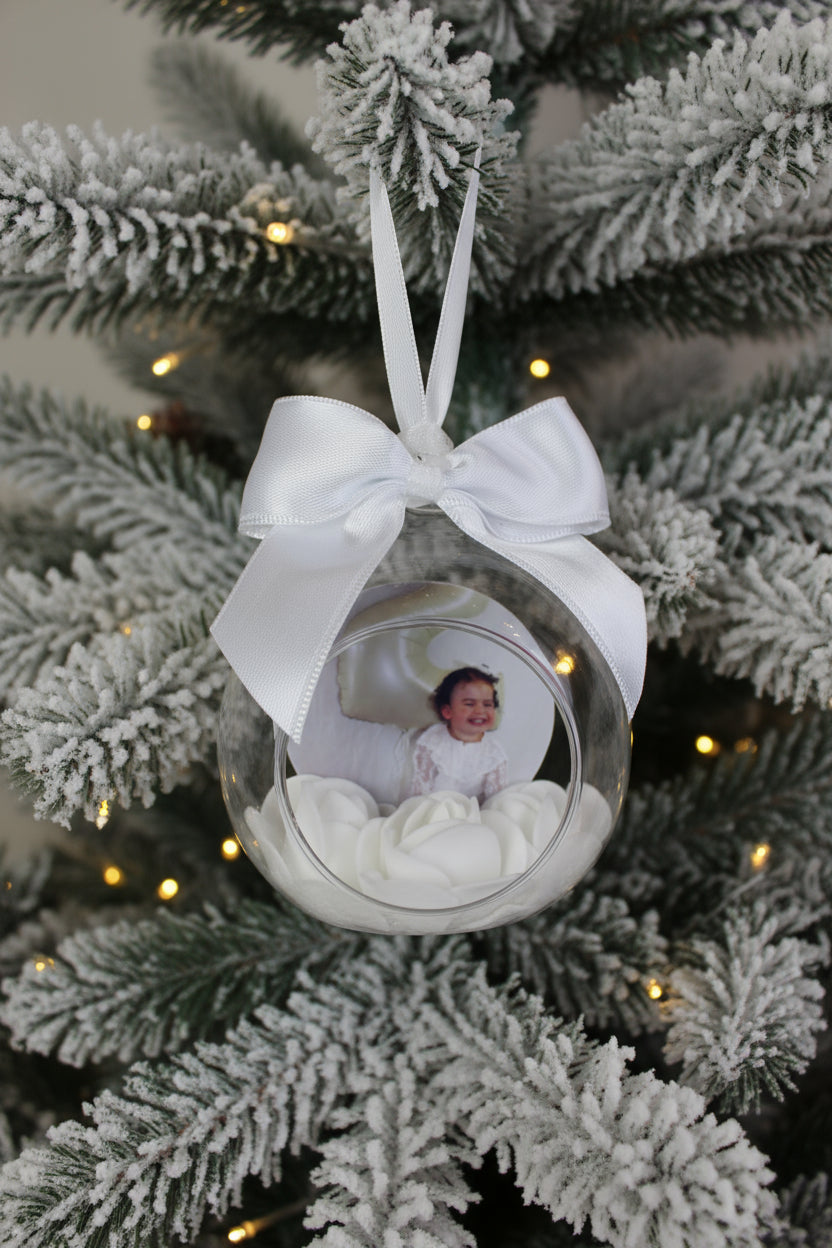Decorative glass ornament with a white ribbon and a photo of a child inside, surrounded by white flowers.